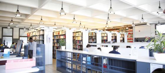 fotografia di una sala studio in biblioteca con studenti e scaffali di libri