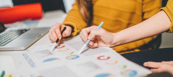 studenti che evidenziano dei grafici su dei fogli posati sulla scrivania 